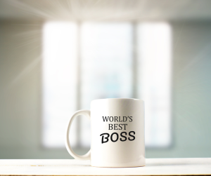 A mug with "World's Best Boss" sits on top of a counter with a sunny window in the background.